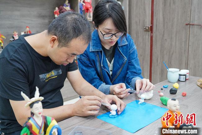 <a target='_blank'  data-cke-saved- >中新社</a>記者(右)現(xiàn)場體驗面塑制作過程?！￡悹帍?攝