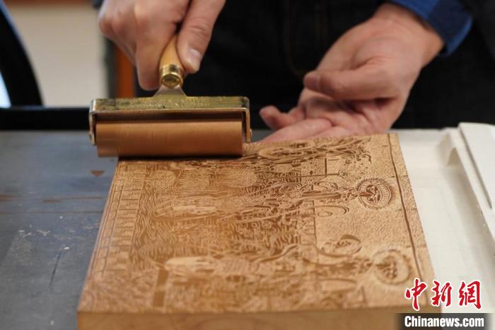 圖為徐晉林工作室工作人員正在給雕好壁畫的版面滾油墨。　九美旦增 　攝