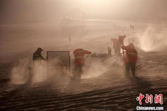 圖為敦煌市鳴沙山月牙泉景區(qū)“駱駝保姆”清理駱駝糞便?！垥粤?攝
