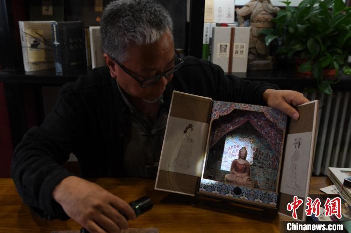 圖為讀者出版集團(tuán)讀者晉林工作室獨(dú)立出品人徐晉林，展示互動性強(qiáng)的敦煌題材手工書。(資料圖) 楊艷敏 攝