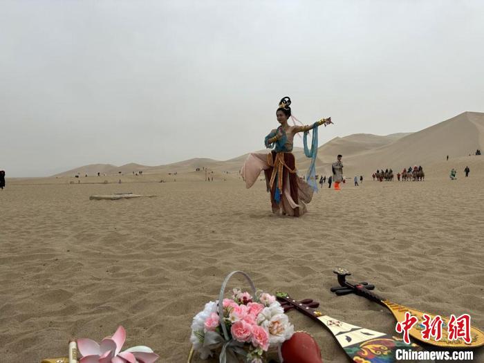 圖為2023年4月底，敦煌大漠“逐舞者”奧楠在鳴沙山月牙泉景區(qū)視頻直播敦煌舞?！●T志軍 攝