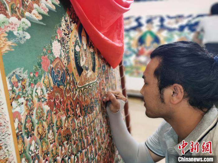 圖為更登才讓的徒弟繪畫唐卡?！?zhí)砀?攝