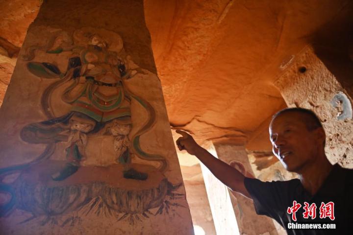 7月15日，甘肅省平?jīng)鍪袥艽h百里石窟長(zhǎng)廊羅漢洞石窟內(nèi)，該窟文保員郭建平介紹窟內(nèi)石刻彩繪壁畫。郭建平家中三代人曾自發(fā)保護(hù)羅漢洞石窟。羅漢洞石窟遺存40余個(gè)窟龕，以北魏至清代風(fēng)格為主。中新社記者 李亞龍 攝</p>
<p>